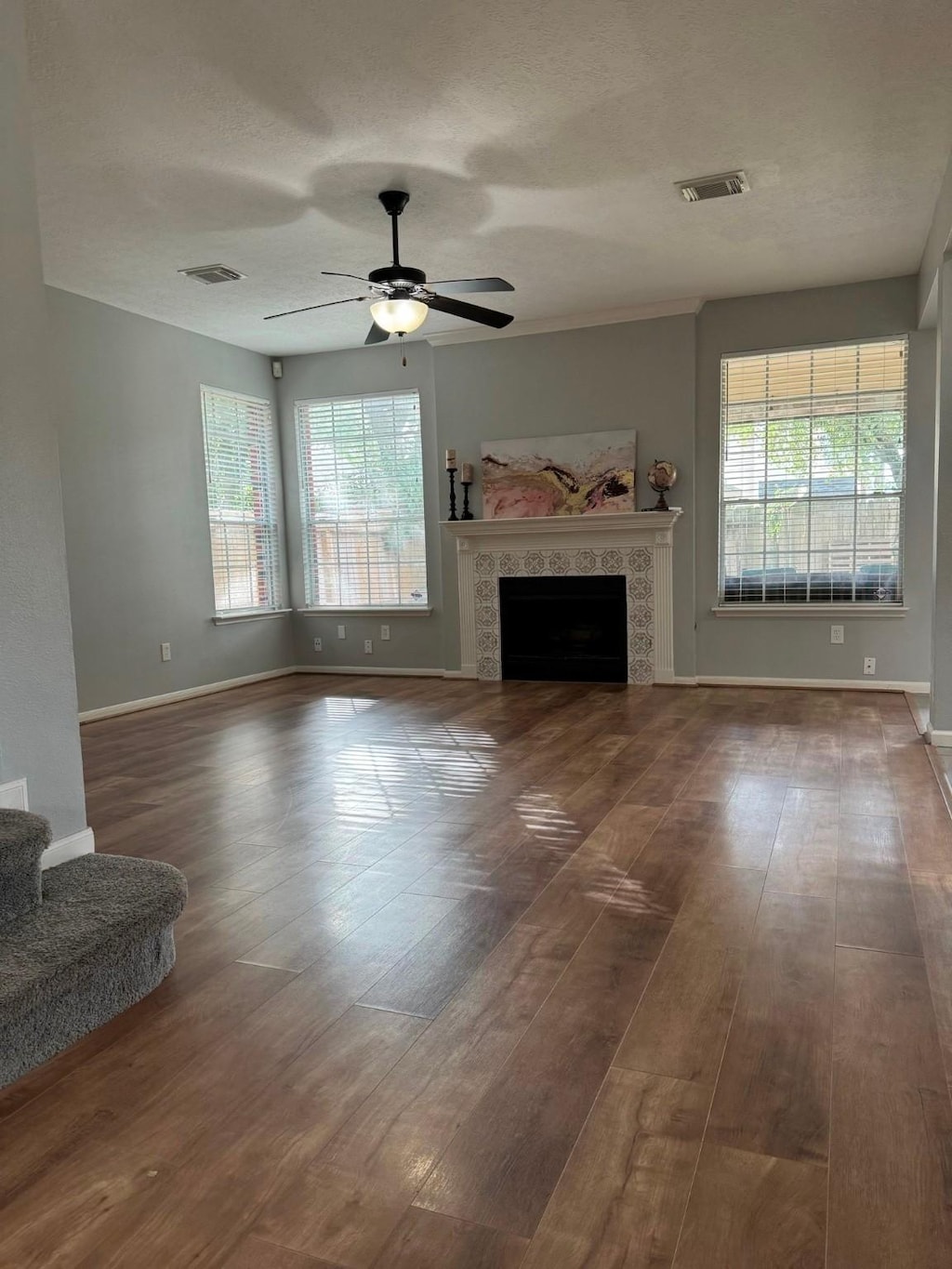 7923 Harvester St, Houston, TX 77095 - unfurnished living room featuring plenty of natural light, ceiling fan, wood finished floors, a tile fireplace, and a textured ceiling