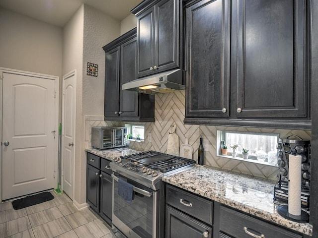 6127 Rosehill Harvest Loop, Katy, TX 77493 - kitchen featuring gas stove, under cabinet range hood, decorative backsplash, light stone counters, and a textured wall