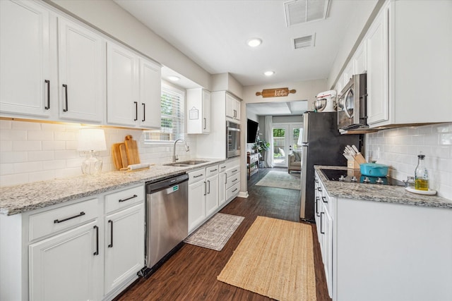 12502 Nova Dr, Houston, TX 77077 - kitchen with stainless steel appliances, dark wood-type flooring, white cabinets, decorative backsplash, and recessed lighting