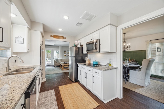 12502 Nova Dr, Houston, TX 77077 - kitchen featuring appliances with stainless steel finishes, dark wood finished floors, white cabinetry, light stone counters, and backsplash