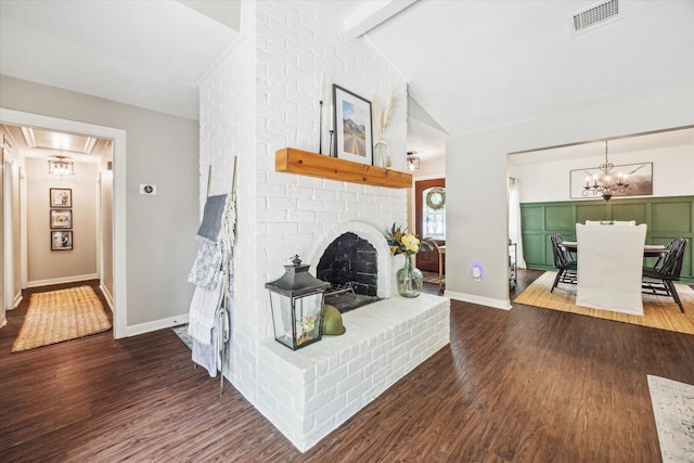 12502 Nova Dr, Houston, TX 77077 - living area featuring attic access, wood finished floors, a chandelier, a brick fireplace, and beam ceiling