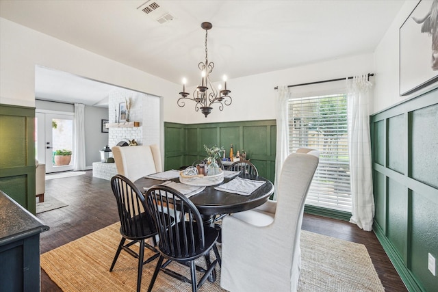 12502 Nova Dr, Houston, TX 77077 - dining room with healthy amount of natural light, a chandelier, a brick fireplace, dark wood-style flooring, and a wainscoted wall