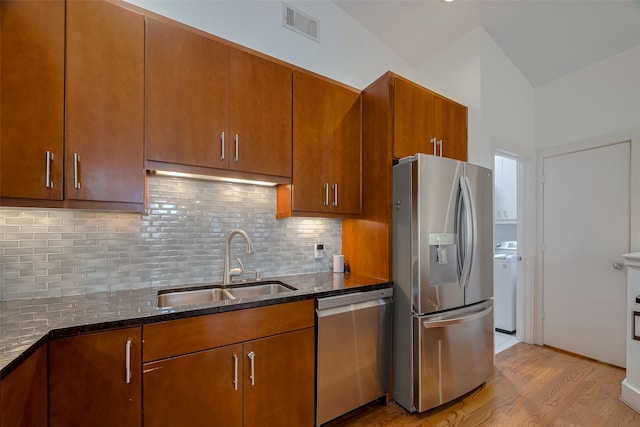 308 Dennis St, Houston, TX 77006 - kitchen with stainless steel appliances, dark stone countertops, tasteful backsplash, brown cabinets, and vaulted ceiling