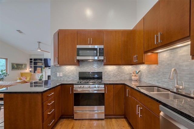 308 Dennis St, Houston, TX 77006 - kitchen featuring appliances with stainless steel finishes, a peninsula, dark stone countertops, decorative backsplash, and lofted ceiling