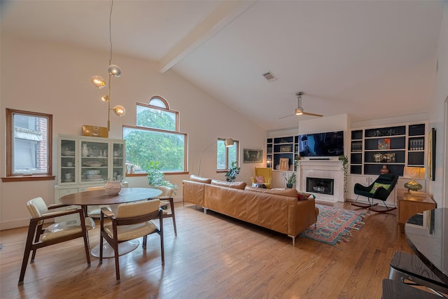 308 Dennis St, Houston, TX 77006 - living area with beam ceiling, light wood finished floors, a ceiling fan, a tiled fireplace, and high vaulted ceiling
