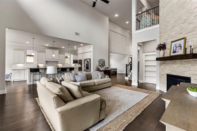 13819 Windward Harbor Ct, Houston, TX 77059 - living room featuring a towering ceiling, a ceiling fan, dark wood-style floors, built in features, and a fireplace