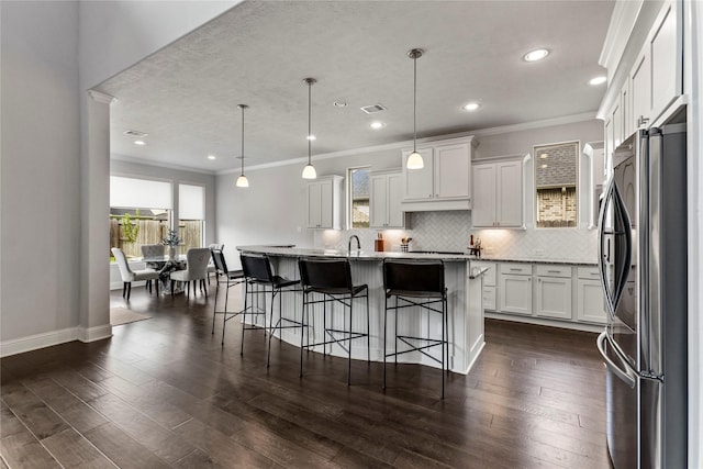 13819 Windward Harbor Ct, Houston, TX 77059 - kitchen with freestanding refrigerator, white cabinets, backsplash, a kitchen bar, and crown molding