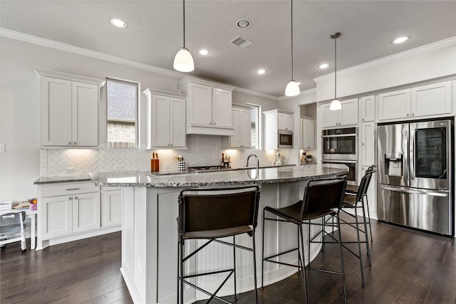 13819 Windward Harbor Ct, Houston, TX 77059 - kitchen with stainless steel appliances, ornamental molding, white cabinets, dark wood-style flooring, and a kitchen island with sink