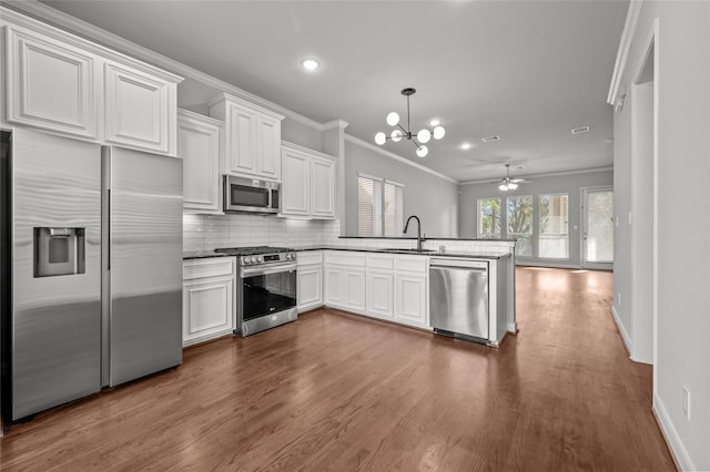 2338 Bastrop St, Houston, TX 77004 - kitchen featuring stainless steel appliances, crown molding, a peninsula, a chandelier, and dark wood-style floors
