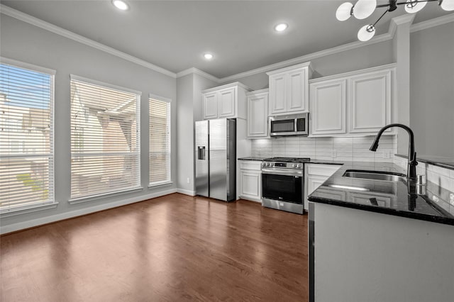 2338 Bastrop St, Houston, TX 77004 - kitchen with appliances with stainless steel finishes, white cabinets, dark wood-style flooring, backsplash, and ornamental molding