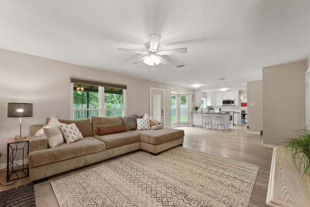 3715 Ember Spring Dr, Kingwood, TX 77339 - living area featuring a ceiling fan, light wood-style floors, and a textured ceiling
