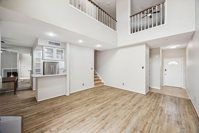 7350 Kirby Dr Unit 46, Houston, TX 77030 - unfurnished living room featuring wood finished floors, stairway, a warm lit fireplace, recessed lighting, and a high ceiling