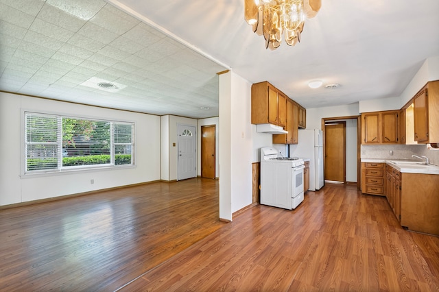 5532 Meadow Creek Ln, Houston, TX 77017 - kitchen with white appliances, under cabinet range hood, wood finished floors, light countertops, and a chandelier