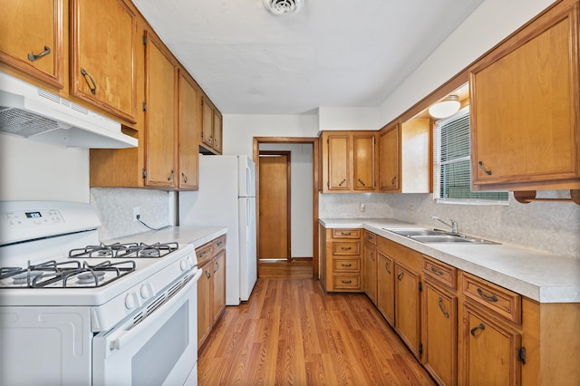 5532 Meadow Creek Ln, Houston, TX 77017 - kitchen with white appliances, under cabinet range hood, light countertops, light wood-style flooring, and brown cabinetry