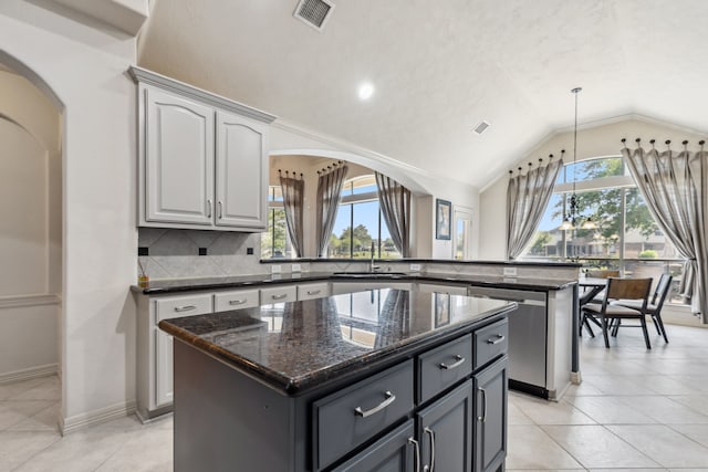 8411 Middle Canyon Rd, Katy, TX 77494 - kitchen featuring dishwasher, a kitchen island, a peninsula, lofted ceiling, and decorative backsplash