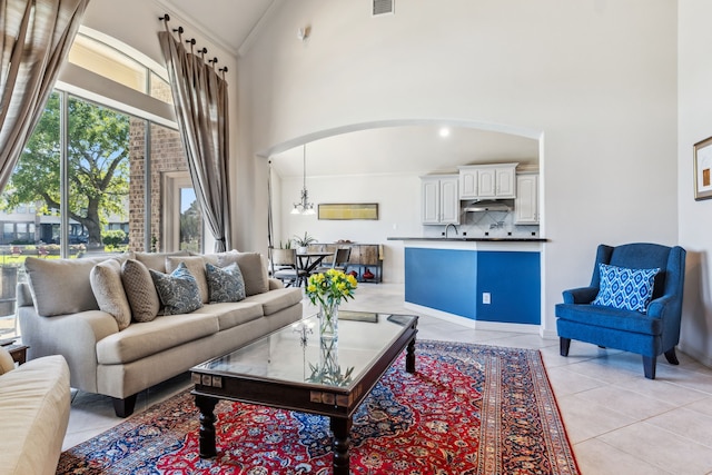 8411 Middle Canyon Rd, Katy, TX 77494 - living room featuring high vaulted ceiling, light tile patterned flooring, crown molding, arched walkways, and a chandelier