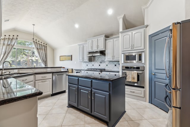 8411 Middle Canyon Rd, Katy, TX 77494 - kitchen featuring stainless steel appliances, lofted ceiling, decorative backsplash, a center island, and light tile patterned flooring