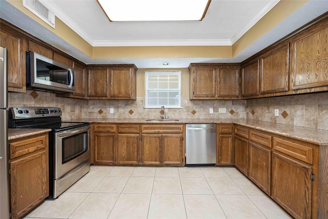 11510 Pagoda Dr, Houston, TX 77477 - kitchen with appliances with stainless steel finishes, tasteful backsplash, light tile patterned floors, light stone counters, and crown molding