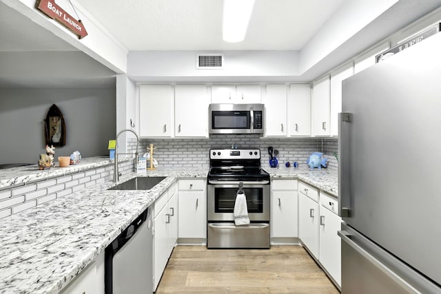 100 Edgewater Dr Unit 39, Livingston, TX 77351 - kitchen featuring stainless steel appliances, light wood-type flooring, white cabinets, and decorative backsplash