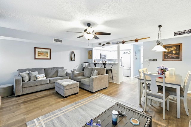 100 Edgewater Dr Unit 39, Livingston, TX 77351 - living room with light wood-style floors, ceiling fan, and a textured ceiling