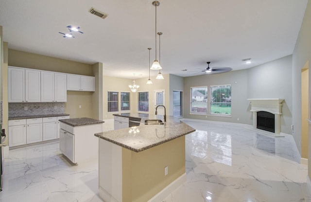 18327 Bluewater Cove Dr, Humble, TX 77346 - kitchen featuring light marble finish floors, a spacious island, a ceiling fan, backsplash, and a chandelier