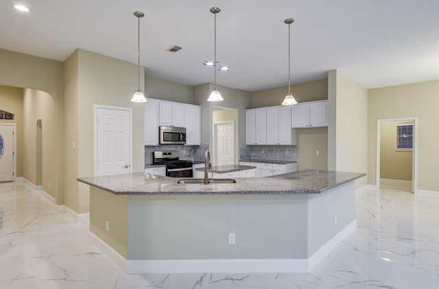 18327 Bluewater Cove Dr, Humble, TX 77346 - kitchen with stainless steel appliances, light marble finish floors, a large island with sink, decorative backsplash, and white cabinets