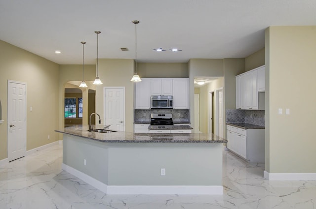 18327 Bluewater Cove Dr, Humble, TX 77346 - kitchen featuring appliances with stainless steel finishes, arched walkways, a large island, light marble finish flooring, and backsplash