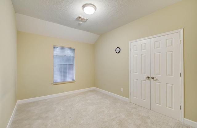 18327 Bluewater Cove Dr, Humble, TX 77346 - unfurnished bedroom featuring light carpet, vaulted ceiling, a closet, and a textured ceiling