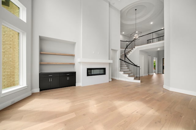 1749 Parana Dr, Houston, TX 77080 - unfurnished living room featuring a high ceiling, light wood-type flooring, a glass covered fireplace, stairs, and a chandelier