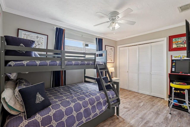 4004 Ector Dr, Galveston, TX 77554 - bedroom featuring wood finished floors, a closet, crown molding, a textured ceiling, and ceiling fan
