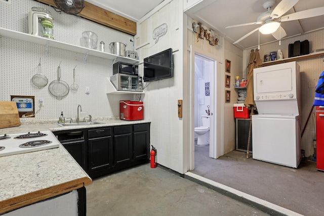4004 Ector Dr, Galveston, TX 77554 - kitchen featuring open shelves, stacked washing machine and dryer, dark cabinets, concrete floors, and light countertops