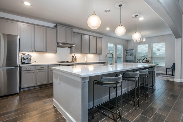 21207 Bradford Grove Dr, Spring, TX 77379 - kitchen featuring freestanding refrigerator, gray cabinets, dark wood-type flooring, backsplash, and an island with sink