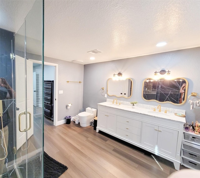 606 E Ahldag St, Wharton, TX 77488 - bathroom featuring a textured ceiling, wood finished floors, double vanity, a shower stall, and a bidet