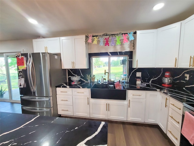 606 E Ahldag St, Wharton, TX 77488 - kitchen with freestanding refrigerator, dark wood finished floors, white cabinetry, dark countertops, and decorative backsplash
