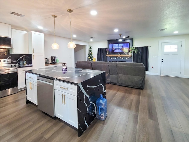 606 E Ahldag St, Wharton, TX 77488 - kitchen with appliances with stainless steel finishes, dark countertops, white cabinets, dark wood finished floors, and recessed lighting
