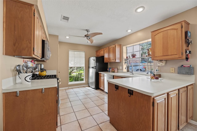 7615 Sandygate Ln, Houston, TX 77095 - kitchen with appliances with stainless steel finishes, plenty of natural light, a peninsula, light countertops, and a textured ceiling
