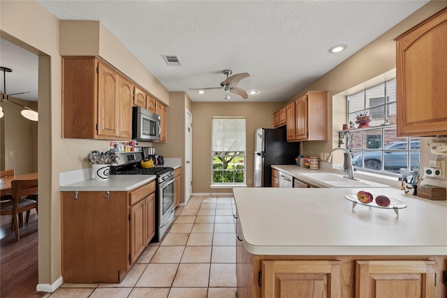 7615 Sandygate Ln, Houston, TX 77095 - kitchen featuring appliances with stainless steel finishes, light countertops, ceiling fan, light tile patterned flooring, and a peninsula