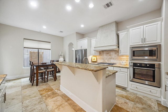 961 Queen Annes Rd, Houston, TX 77024 - kitchen with stainless steel appliances, custom range hood, light stone counters, tasteful backsplash, and recessed lighting