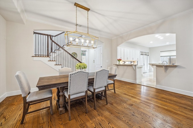 961 Queen Annes Rd, Houston, TX 77024 - dining area with arched walkways, wood finished floors, stairs, ornamental molding, and a chandelier