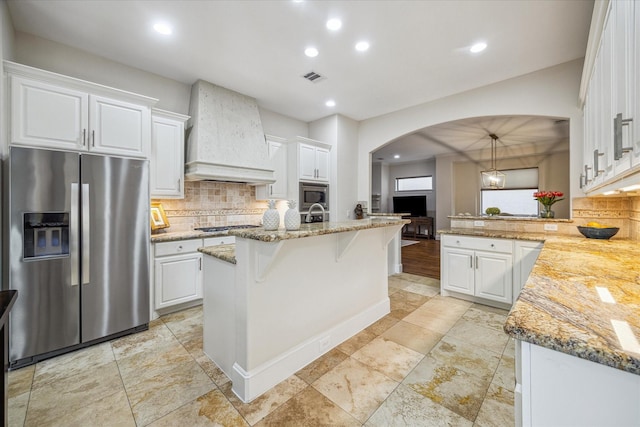 961 Queen Annes Rd, Houston, TX 77024 - kitchen with stainless steel appliances, custom exhaust hood, arched walkways, backsplash, and white cabinetry