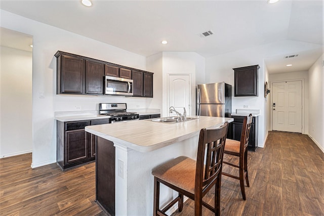 16862 Short Pines Dr, Conroe, TX 77302 - kitchen featuring appliances with stainless steel finishes, light countertops, dark wood-style floors, dark brown cabinets, and a breakfast bar area