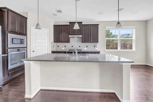 22519 Birch Ridge Meadow Dr, Spring, TX 77389 - kitchen with stainless steel appliances, under cabinet range hood, decorative backsplash, dark wood-style floors, and dark brown cabinetry