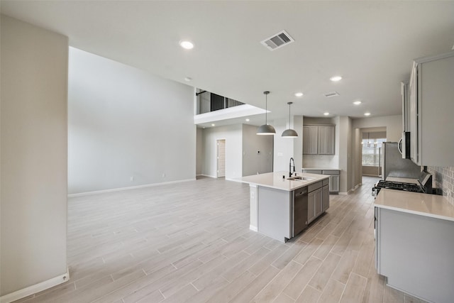 4805 Magnolia Springs Dr, Pearland, TX 77584 - kitchen with gray cabinetry, dishwashing machine, a center island with sink, open floor plan, and light wood-type flooring