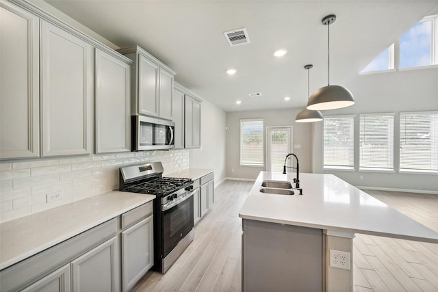 4805 Magnolia Springs Dr, Pearland, TX 77584 - kitchen featuring appliances with stainless steel finishes, a kitchen island with sink, decorative backsplash, recessed lighting, and light wood-style floors
