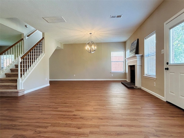 2802 Grants River Cir, Sugar Land, TX 77479 - unfurnished living room featuring light wood-style flooring, a chandelier, a fireplace with raised hearth, and stairway