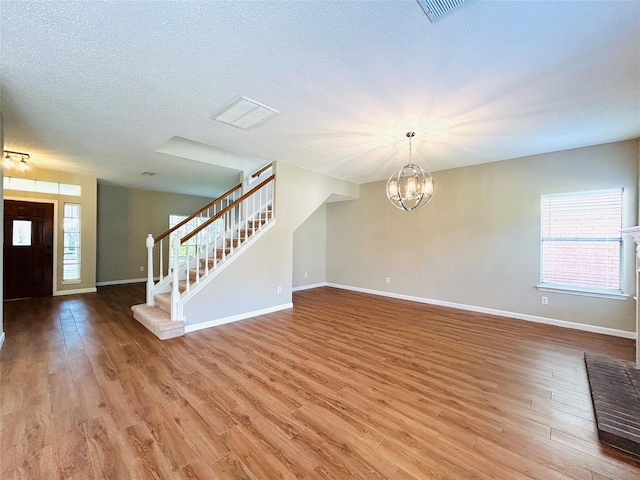 2802 Grants River Cir, Sugar Land, TX 77479 - unfurnished living room with stairs, light wood-style floors, a chandelier, and a textured ceiling