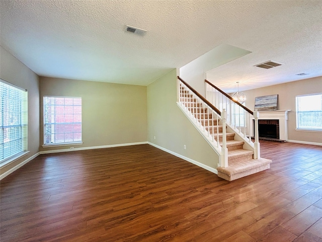 2802 Grants River Cir, Sugar Land, TX 77479 - unfurnished living room with dark wood finished floors, stairs, a textured ceiling, a chandelier, and a fireplace