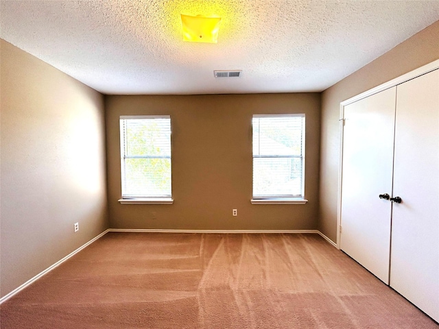 2802 Grants River Cir, Sugar Land, TX 77479 - unfurnished bedroom featuring multiple windows, light carpet, a textured ceiling, and a closet