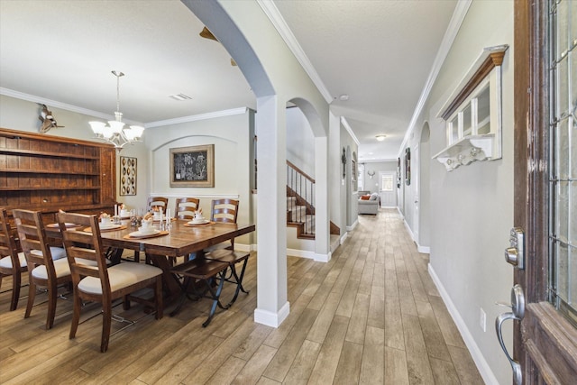 2209 Valley Blossum Ln, League City, TX 77573 - dining area featuring arched walkways, light wood-style flooring, stairway, a chandelier, and ornamental molding