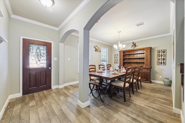 2209 Valley Blossum Ln, League City, TX 77573 - dining room featuring arched walkways, light wood-style flooring, a chandelier, and ornamental molding